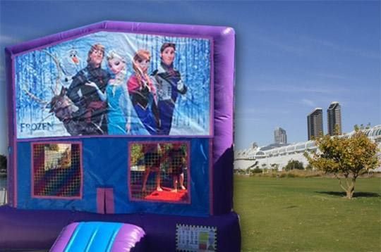 Frozen-themed inflatable bounce house on a grassy field with a city skyline in the background