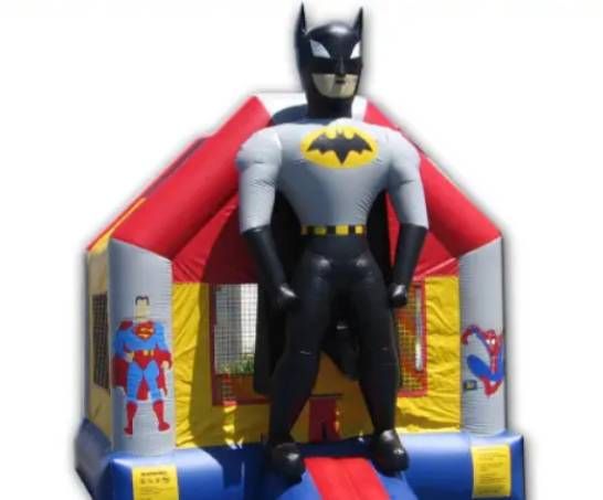 Batman standing in front of a red-and-blue inflatable bounce house
