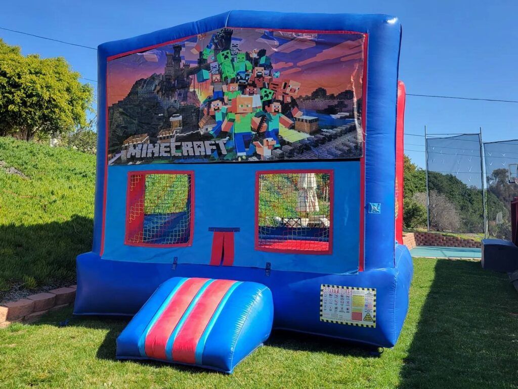 Blue Minecraft-themed bounce house with colorful front slide and mesh windows outdoors