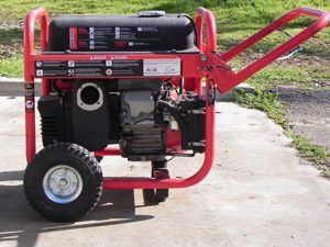 Red portable generator on wheels with a black engine and red frame, sitting on a driveway.