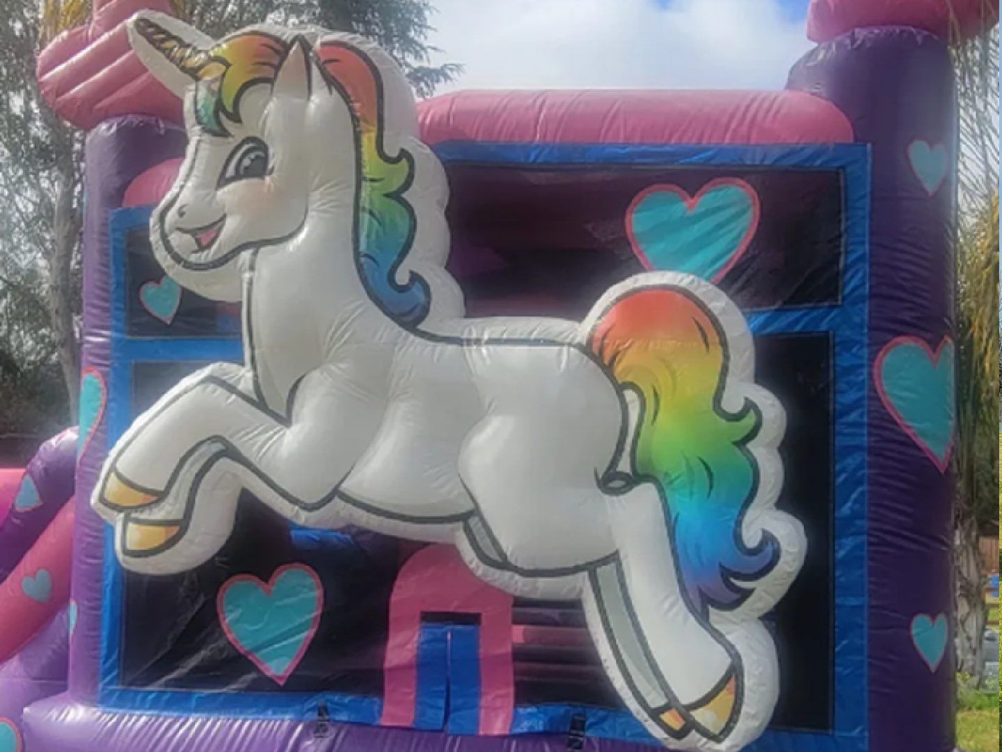 Rainbow unicorn bounce house with blue, pink, and heart decorations