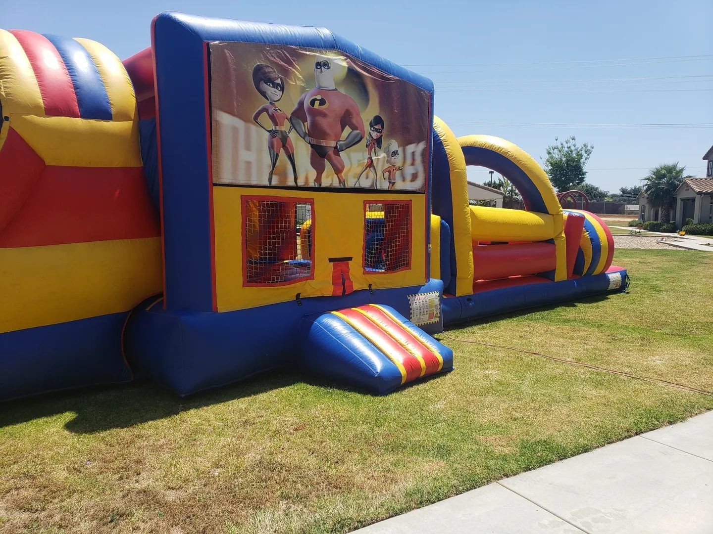Colorful inflatable bounce house with cartoon banner on a sunny grassy field