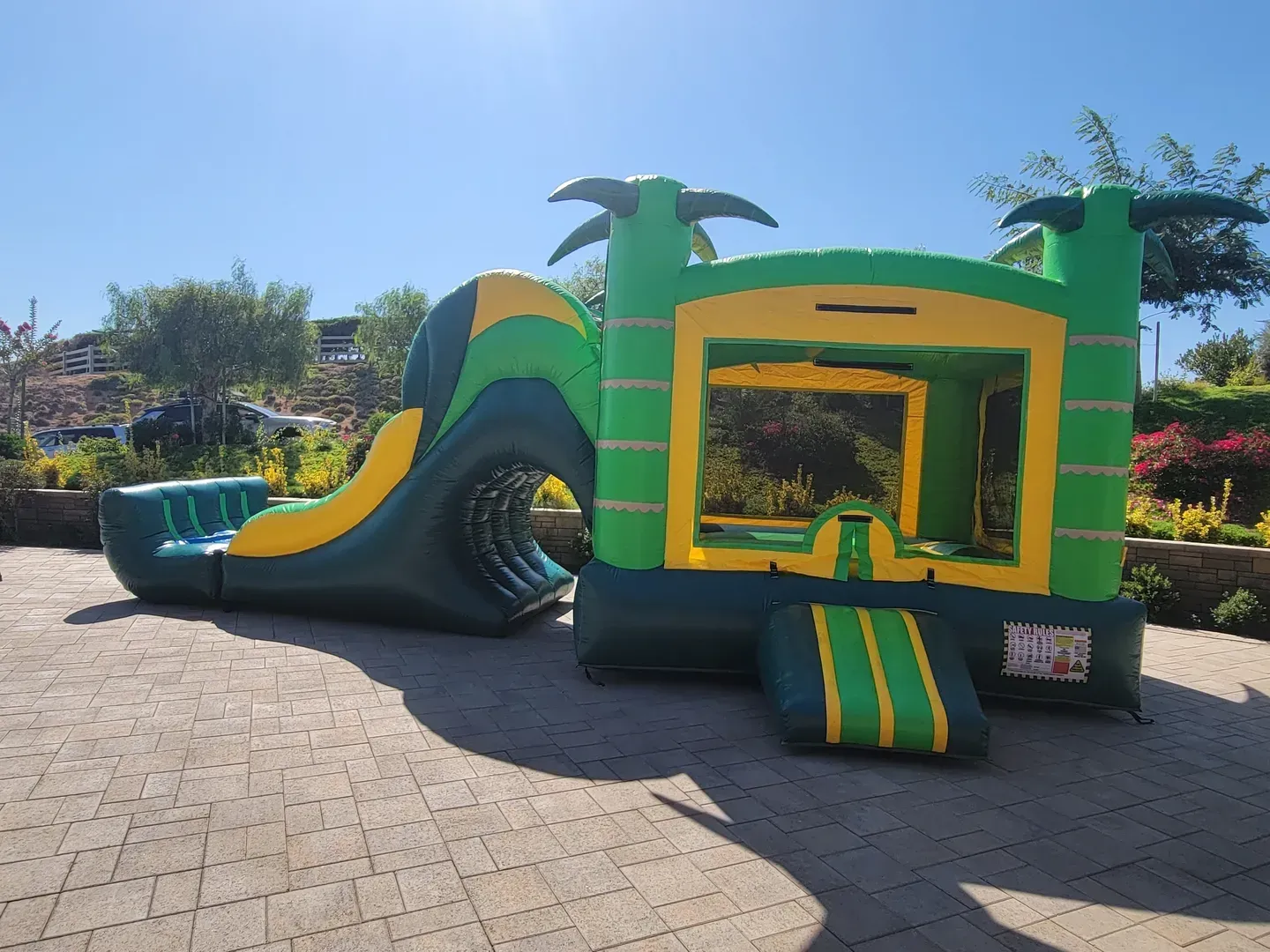 Colorful inflatable bounce house with slide in a sunny outdoor park area