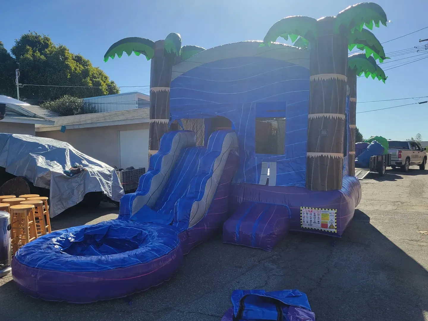 Blue inflatable water slide with palm trees at an outdoor event