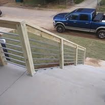 Concrete steps with white railing leading to a yard, with a blue pickup truck parked nearby.