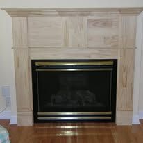 Light wood fireplace mantel with a black fireplace insert and hardwood floor