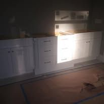 Dimly lit kitchen with white cabinets and a stove, lit by a flashlight or beam of light.