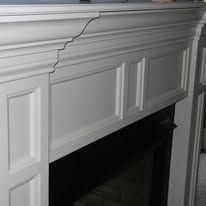 White decorative fireplace mantel with visible crack along the top molding