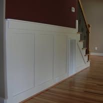 White paneled wainscoting along a staircase in a home interior with hardwood floors and beige walls