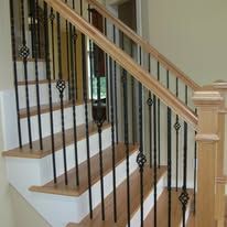 Wooden staircase with white risers, black balusters, and a light wood handrail in a home interior