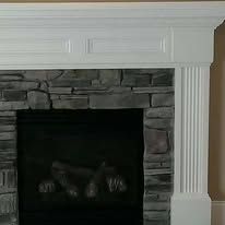 Stone fireplace with black firebox and white decorative mantel in a living room