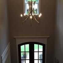 Stairwell with a chandelier above a front door with arched glass panes.