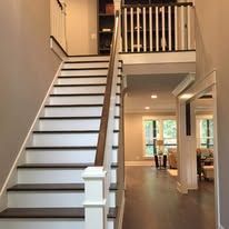 Interior view of a staircase with white risers, dark treads, and an open hallway in a modern home