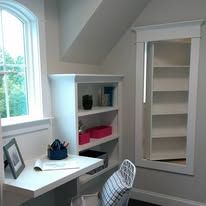 Small home office nook with white desk, shelving, and a chair by a window.