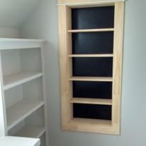 Light wood-framed wall shelf with dark shelves, next to a white shelving unit in a room corner