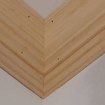Close-up of layered wooden corner molding with visible screws against a white wall