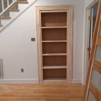 Built-in empty shelving alcove in a hallway with stairs and hardwood floor