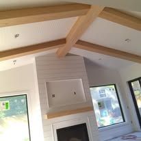 Living room with vaulted ceiling, wooden beams, fireplace, and large windows