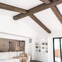 Bright modern living room with exposed wooden ceiling beams and white built-in shelving