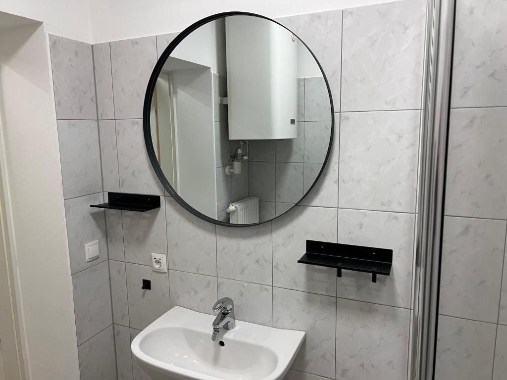 Barrierefreies Badezimmer mit Waschbecken, Spiegel, Haltegriffen und gefliesten Wänden