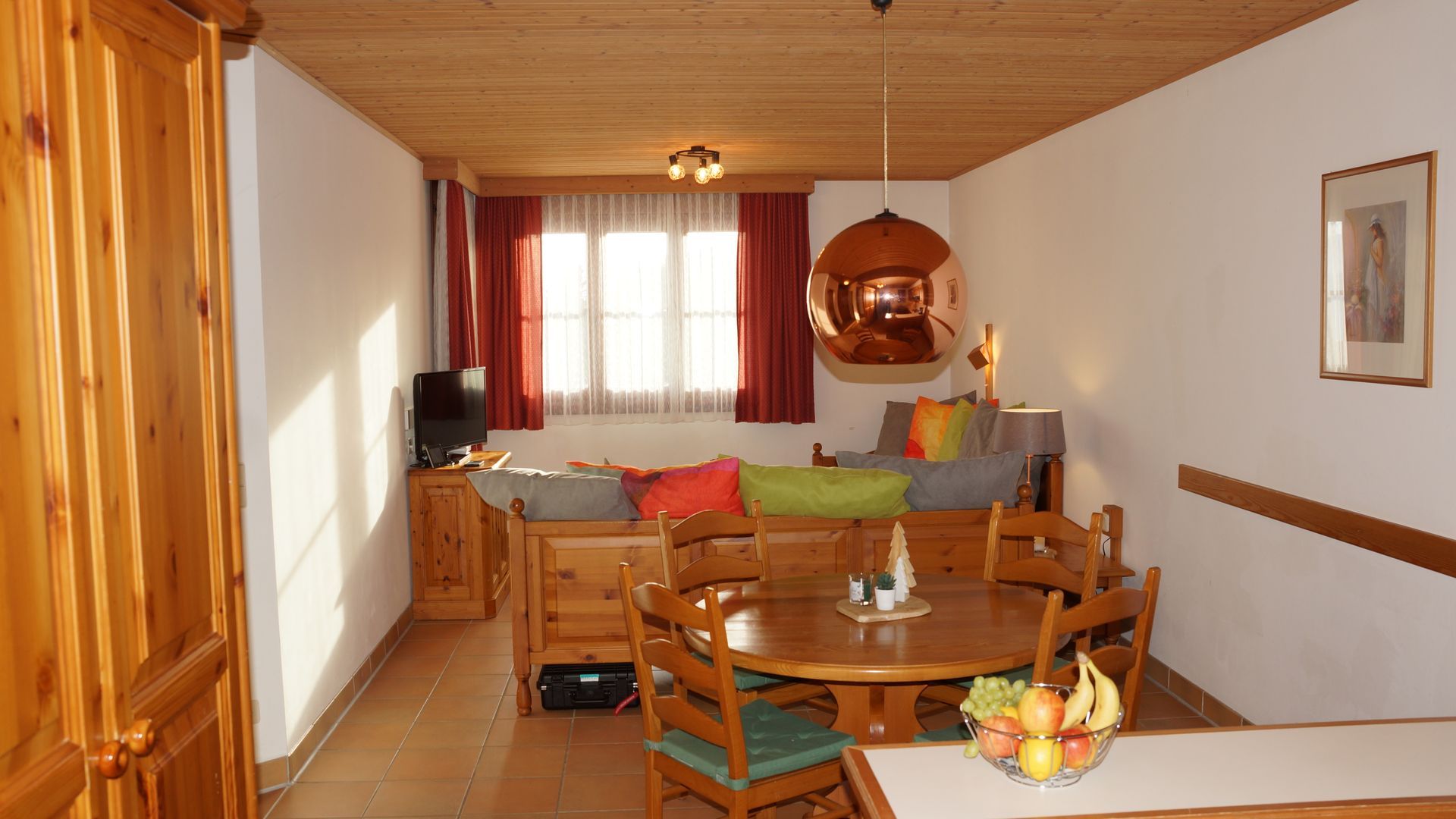 Gemütliches Esszimmer mit Holztisch, Stühlen, warmem Licht und einem Fenster mit Vorhängen.