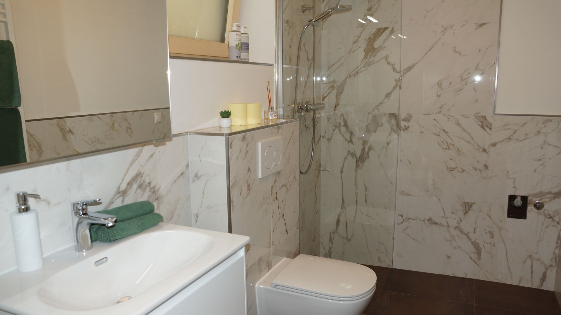 Modernes Badezimmer mit Waschbecken, Toilette, Marmordusche und dunklem Holzboden