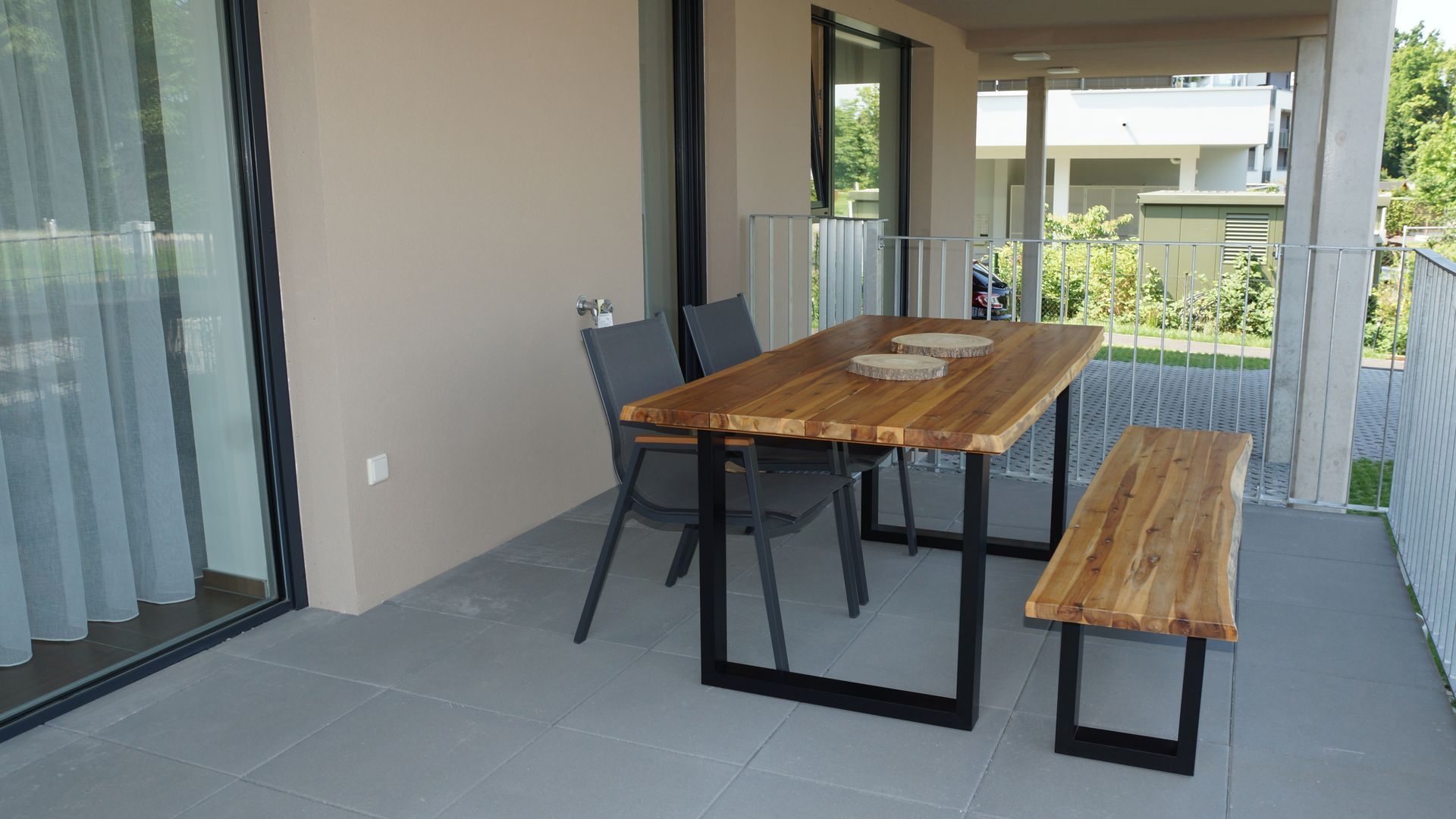 Überdachte Terrasse mit Esstisch, Bank und Stuhl aus Holz neben Glasschiebetüren