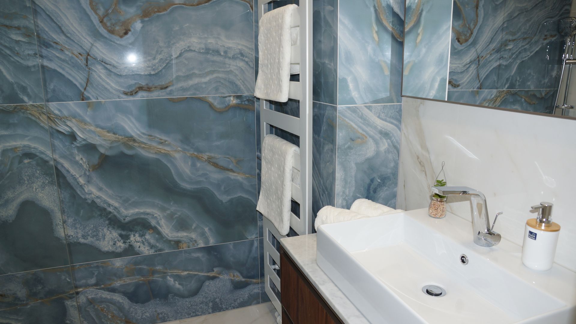 Modernes Badezimmer mit blauen Marmorwänden, einem Waschbecken und einer Duschkabine aus Glas