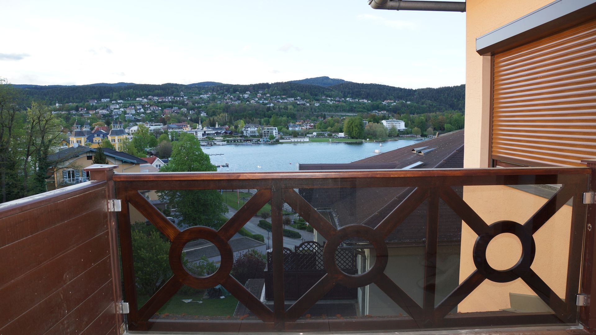 Blick von einem Balkon über eine Bucht und eine Stadt am Hang, im Vordergrund ein Holzgeländer