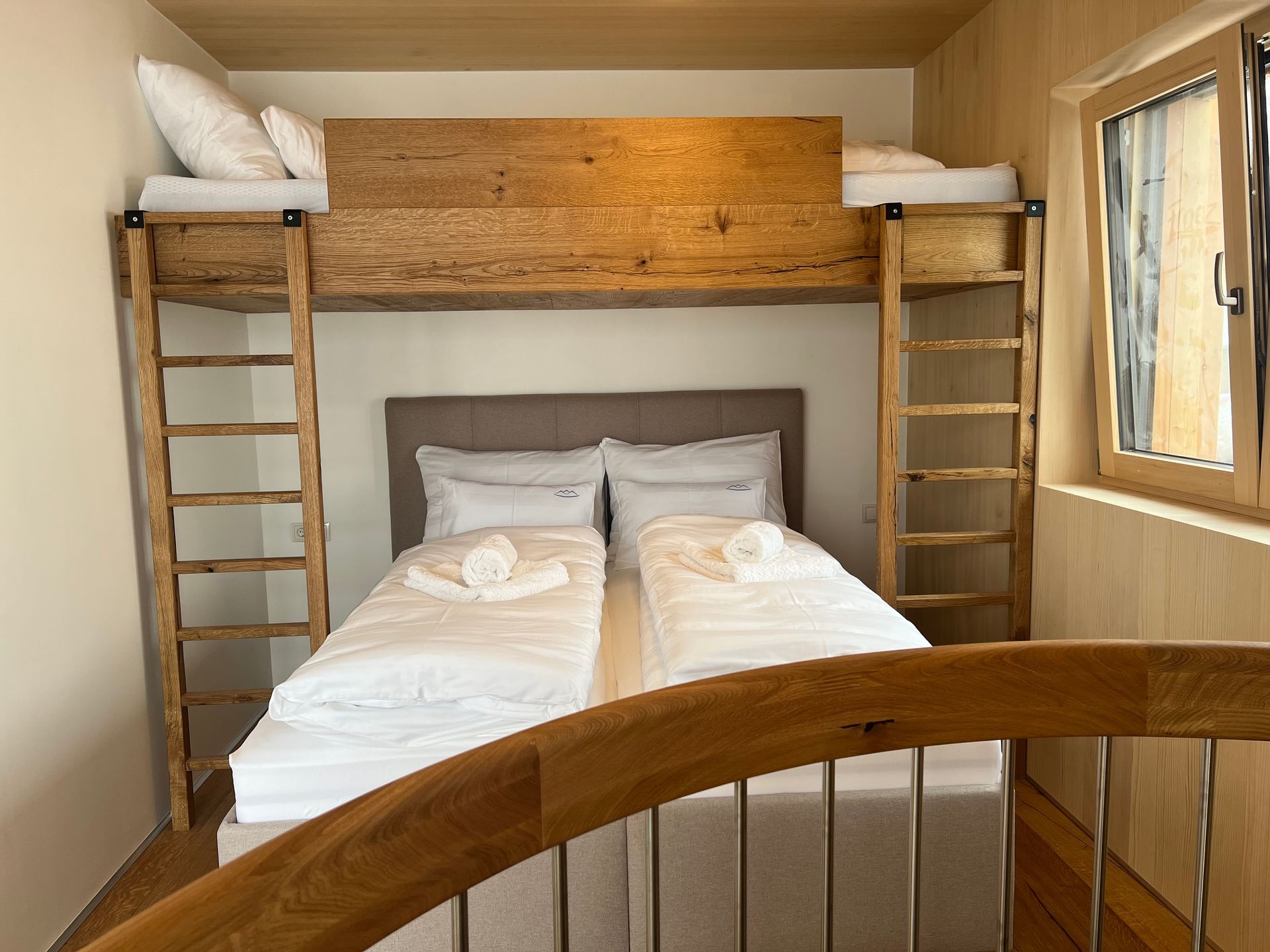 Kompaktes Etagenbettzimmer mit zwei Einzelbetten, Holzwänden und einem Fenster