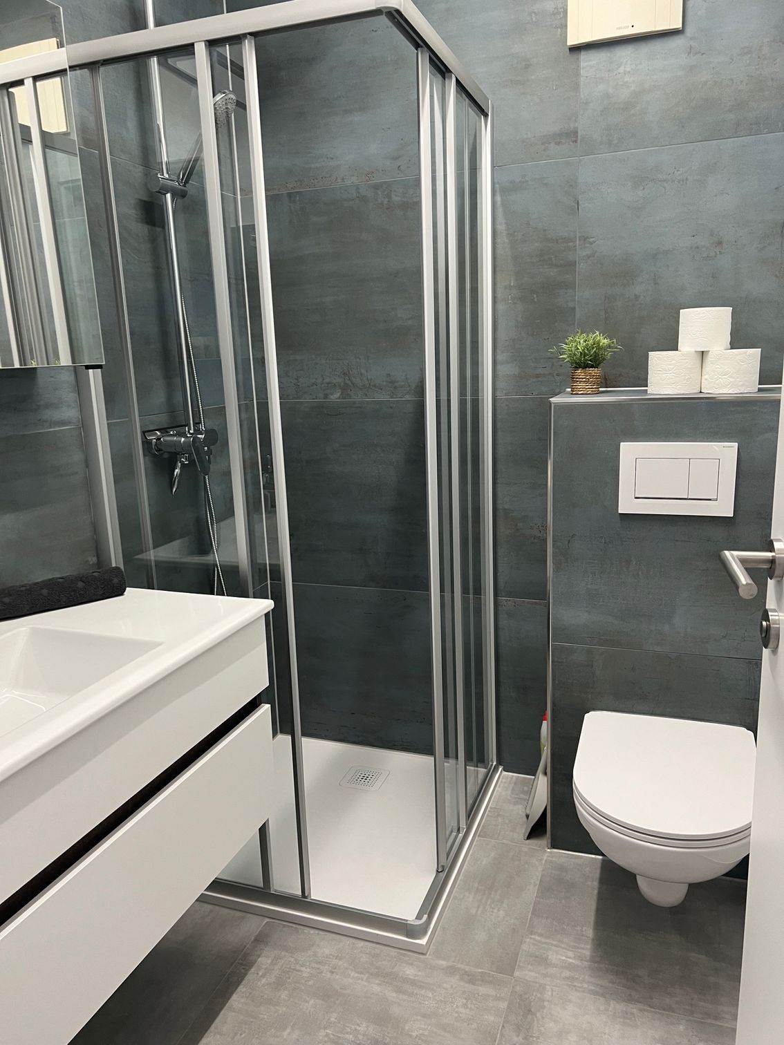 Modernes Badezimmer mit Glasdusche, weißem Waschtisch und wandhängendem WC