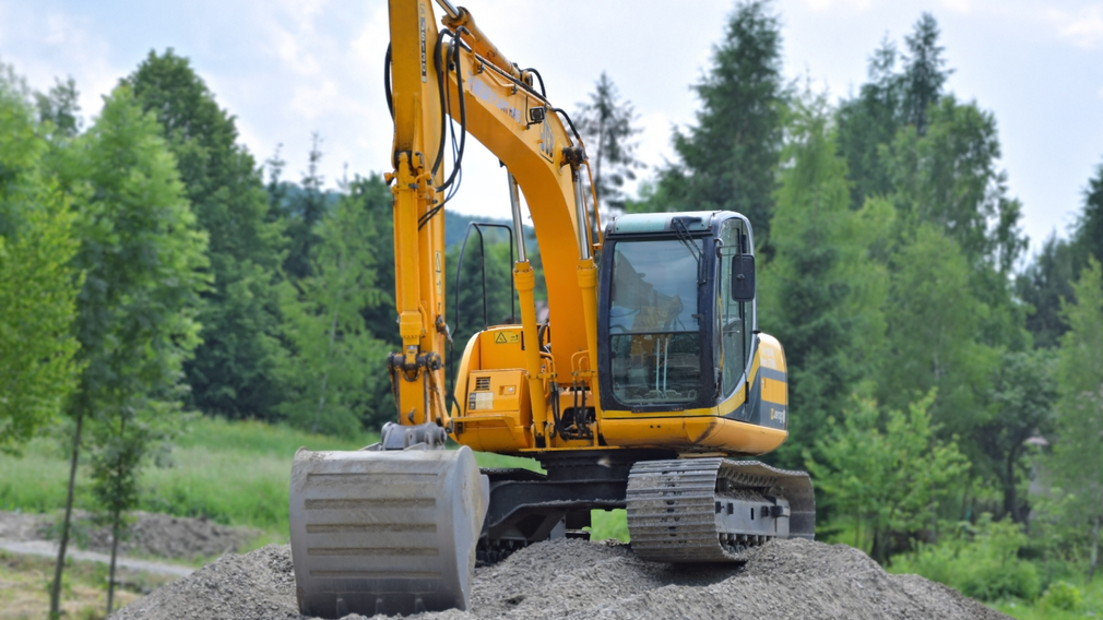 Yellow excavator on a gravel pile in a wooded area