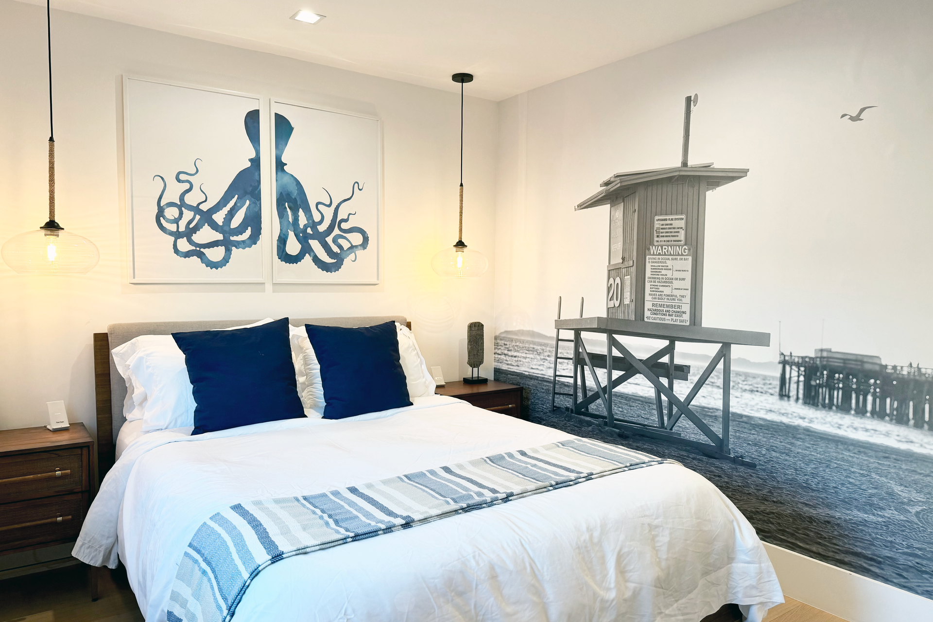 Guest bedroom with blue octopus wall art and coastal pier mural at Newport Retreat