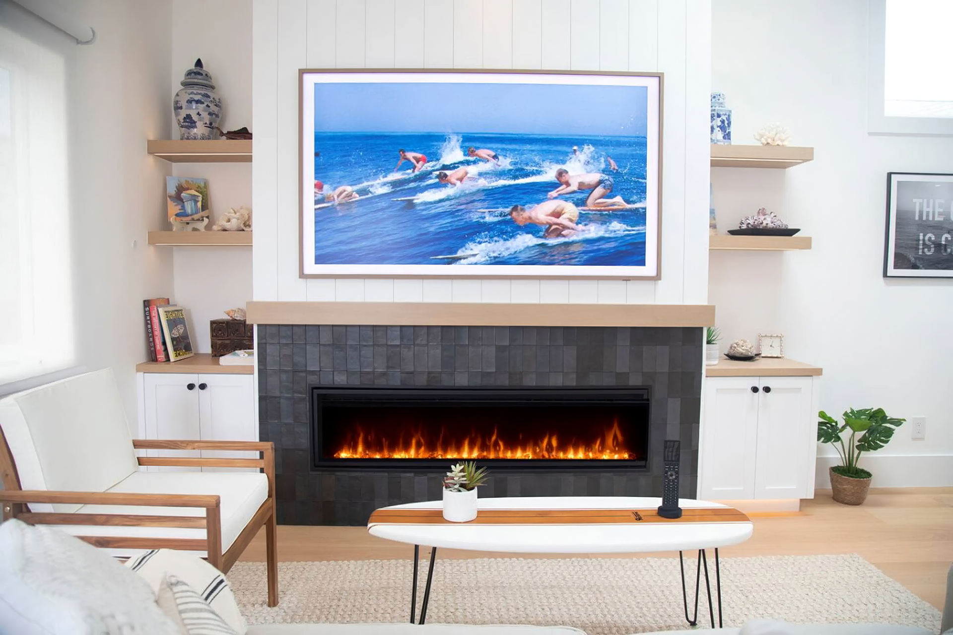 Modern living room with a lit fireplace, ocean painting, and white chairs and shelves