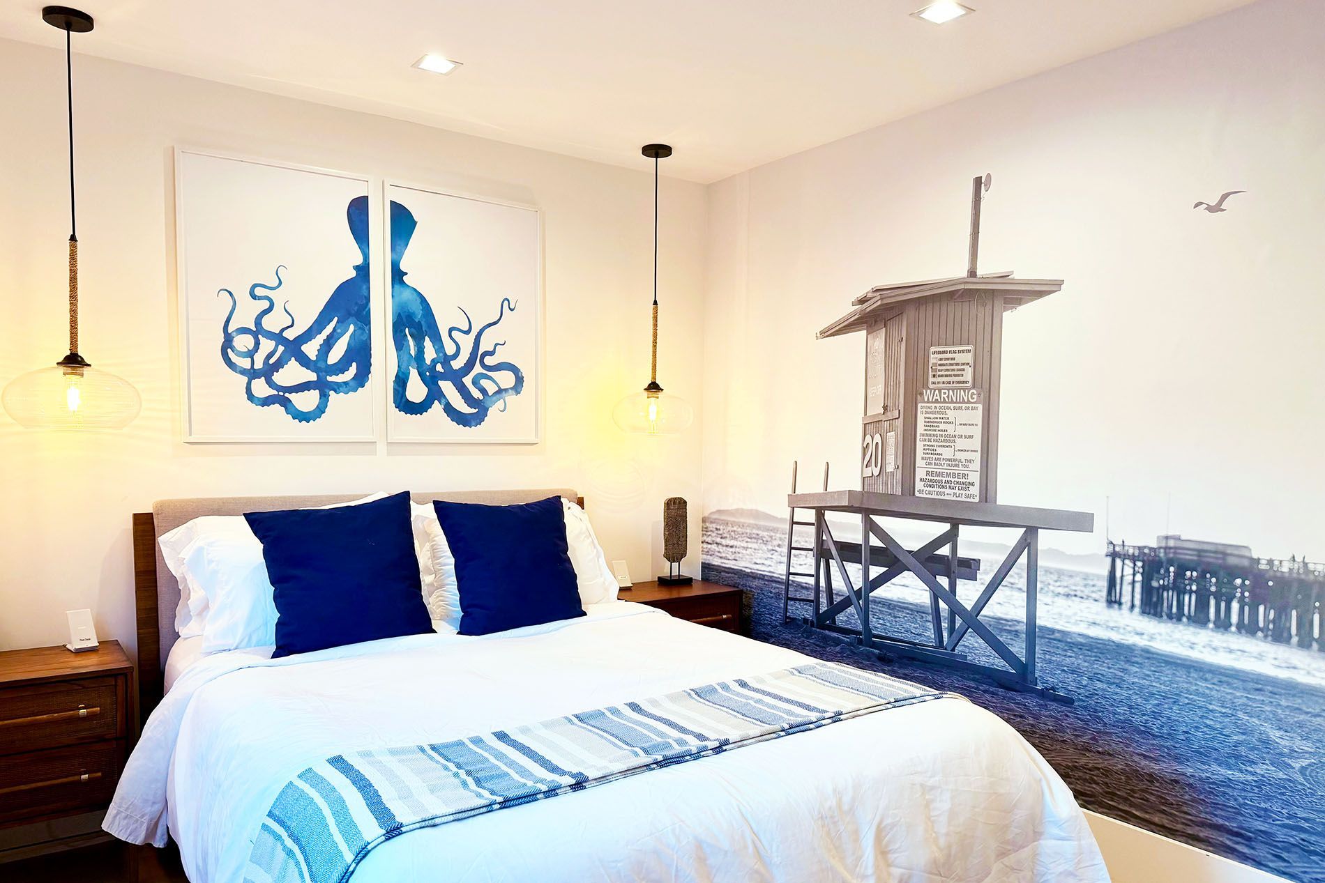 Guest bedroom with blue octopus wall art and coastal pier mural at Newport Retreat