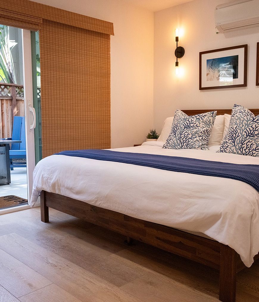 Surf Casita primary bedroom with king bed, bamboo shades and sliding door to the patio