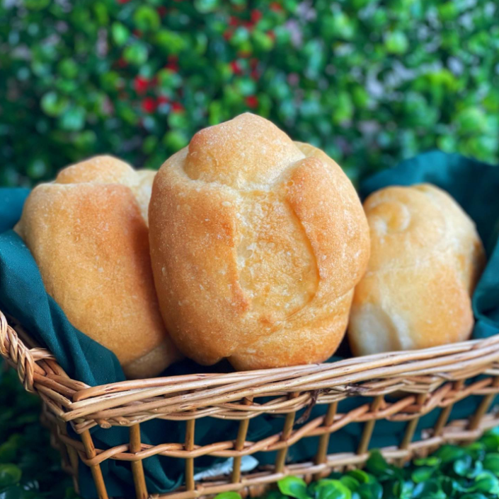 Uma cesta de vime cheia de pãezinhos sobre um pano verde