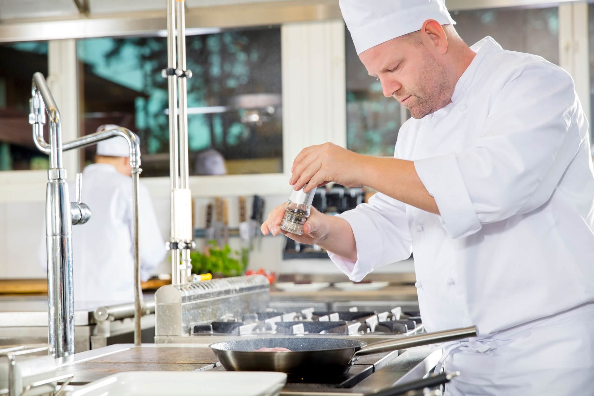 Um chef está preparando comida em uma cozinha.