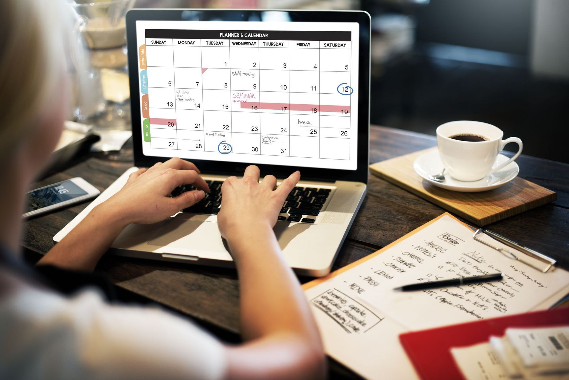 Uma pessoa está digitando em um laptop com um calendário na tela.