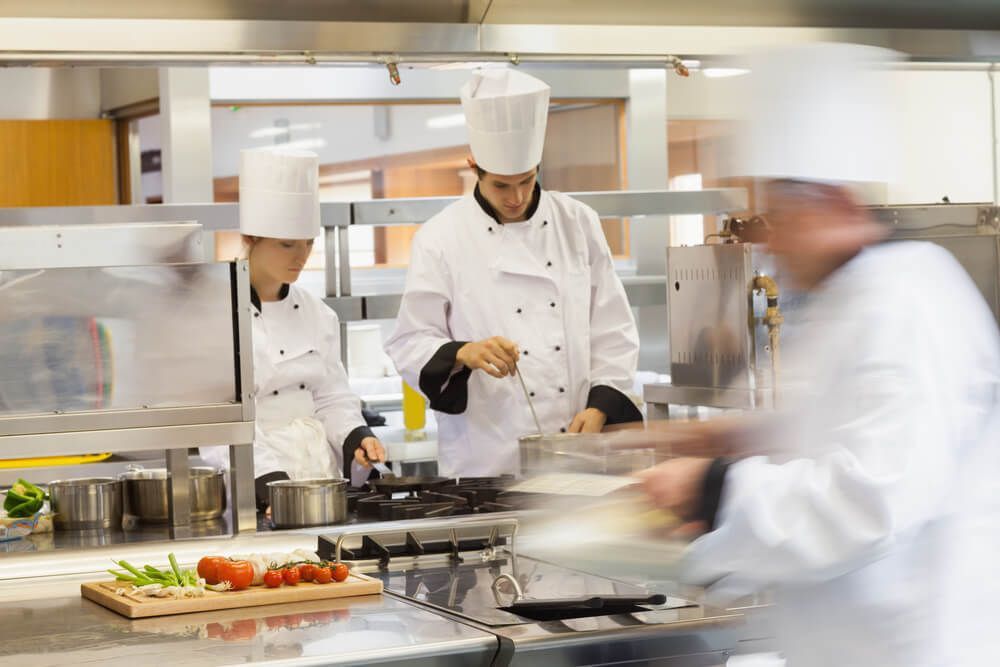 Um grupo de chefs está preparando comida em uma cozinha.