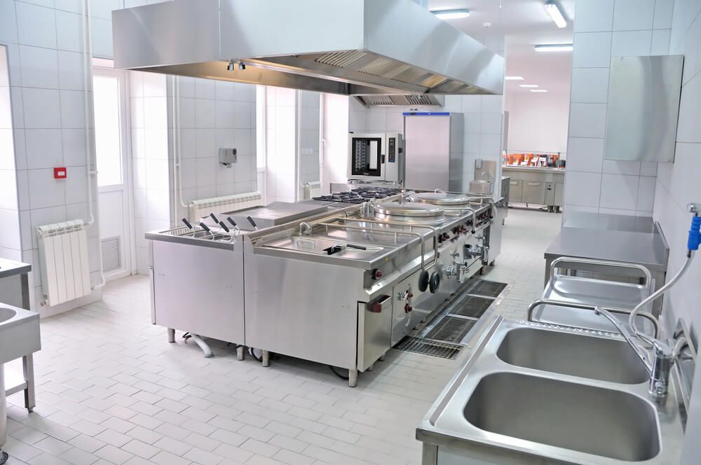 Uma cozinha com muitos eletrodomésticos e pias de aço inoxidável.
