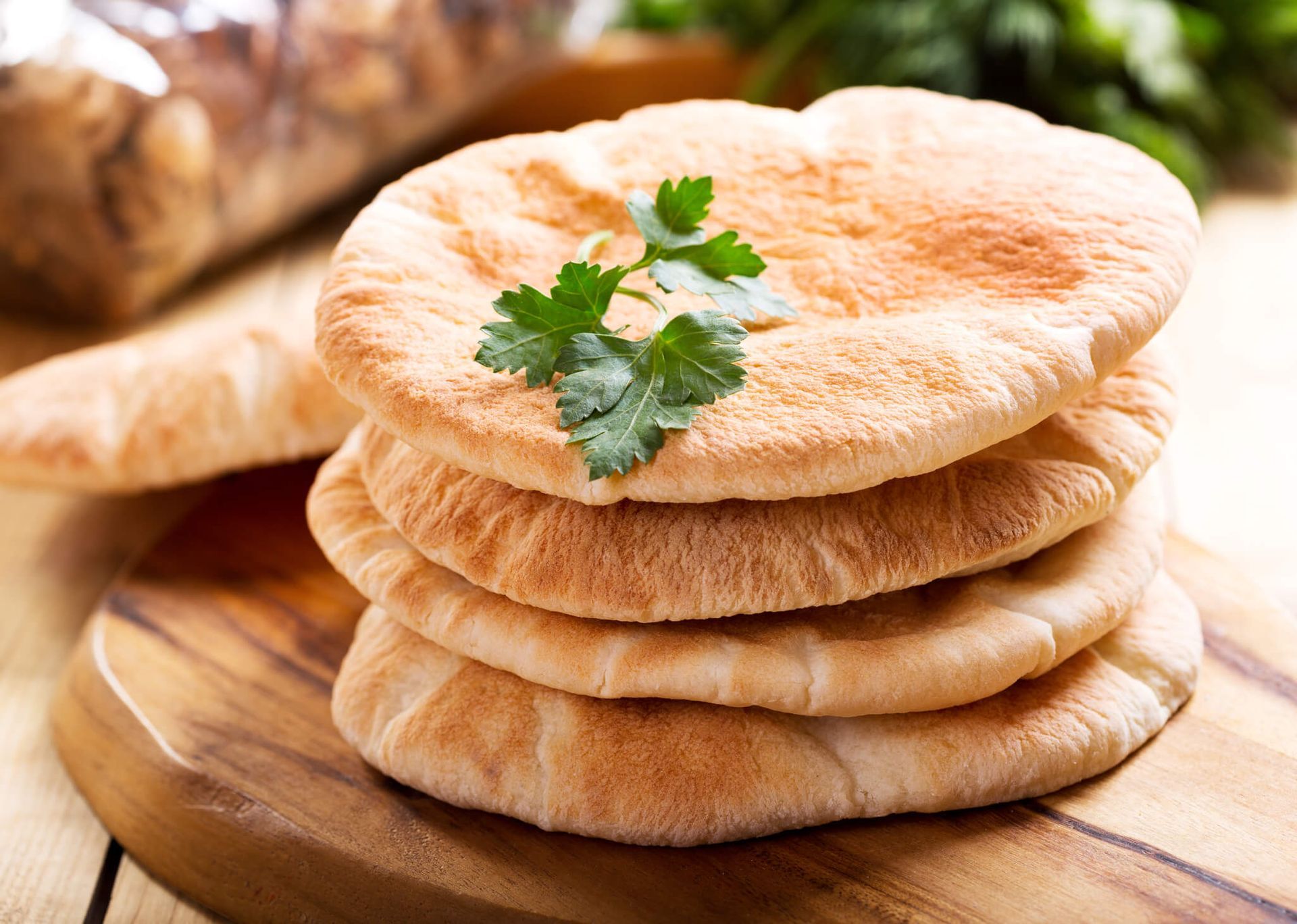 O pão pita é empilhado um sobre o outro em uma tábua de corte de madeira.