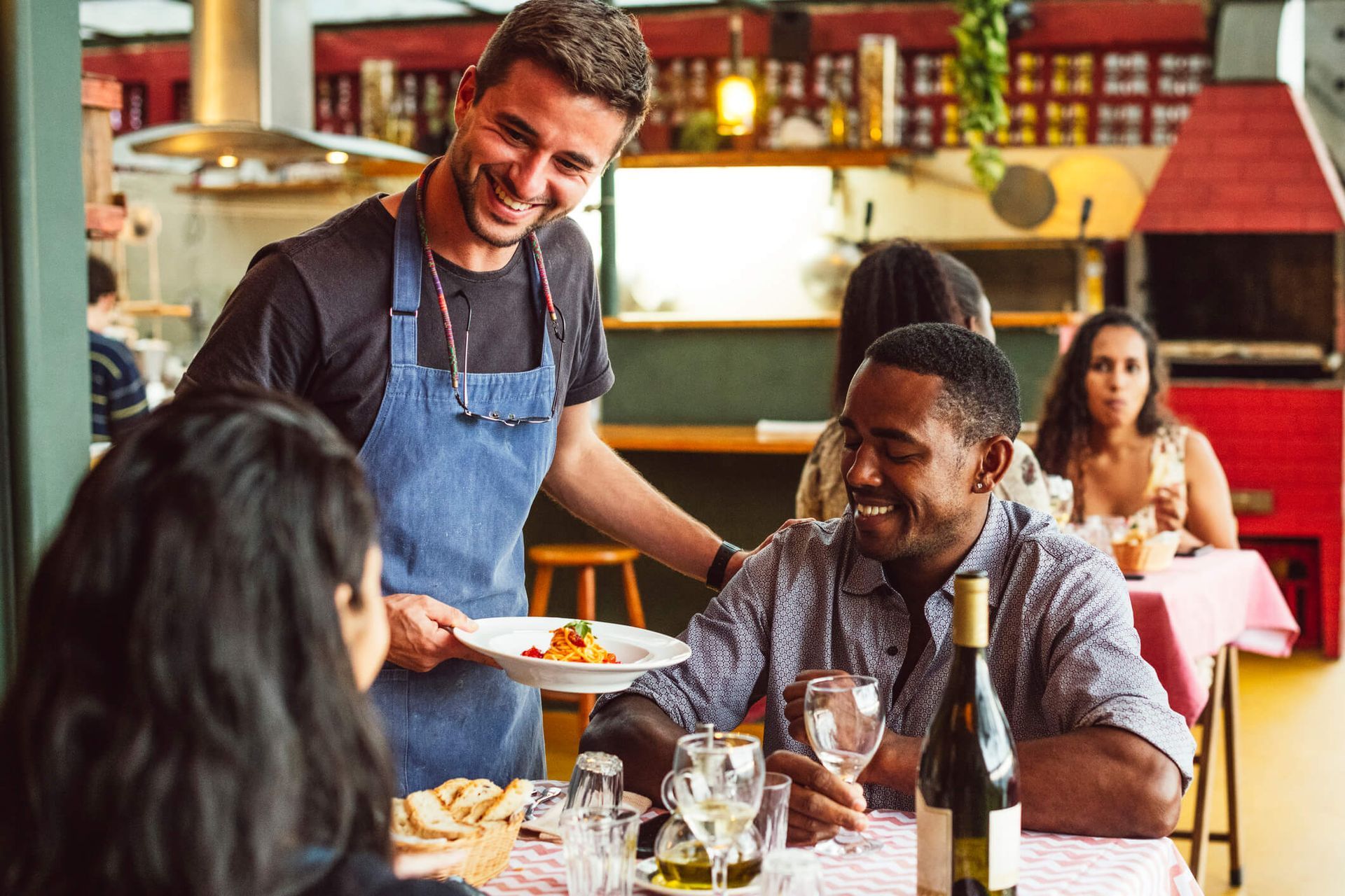 Um garçom está servindo comida para um grupo de pessoas em um restaurante.