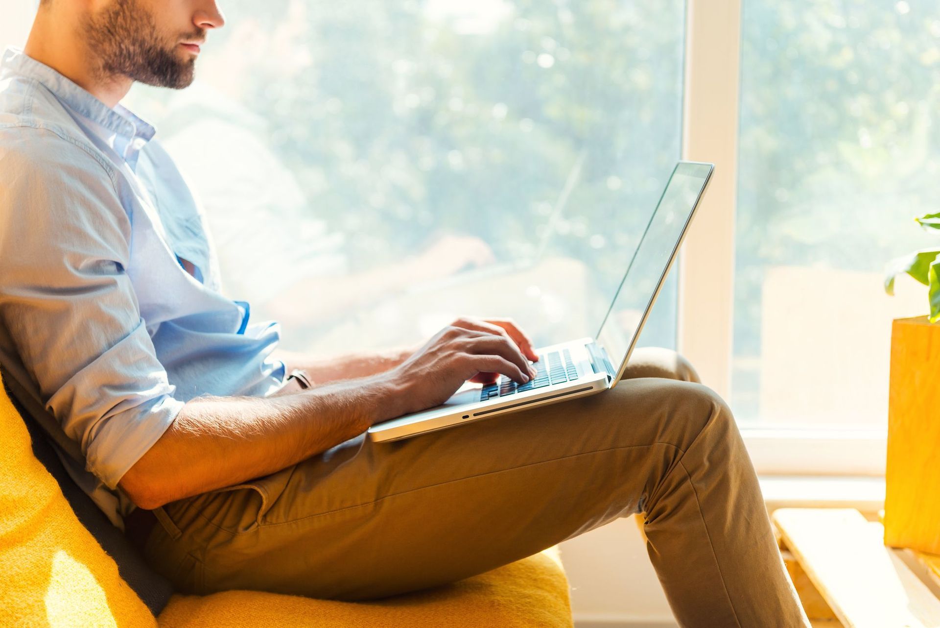 Um homem está sentado em uma cadeira usando um laptop.