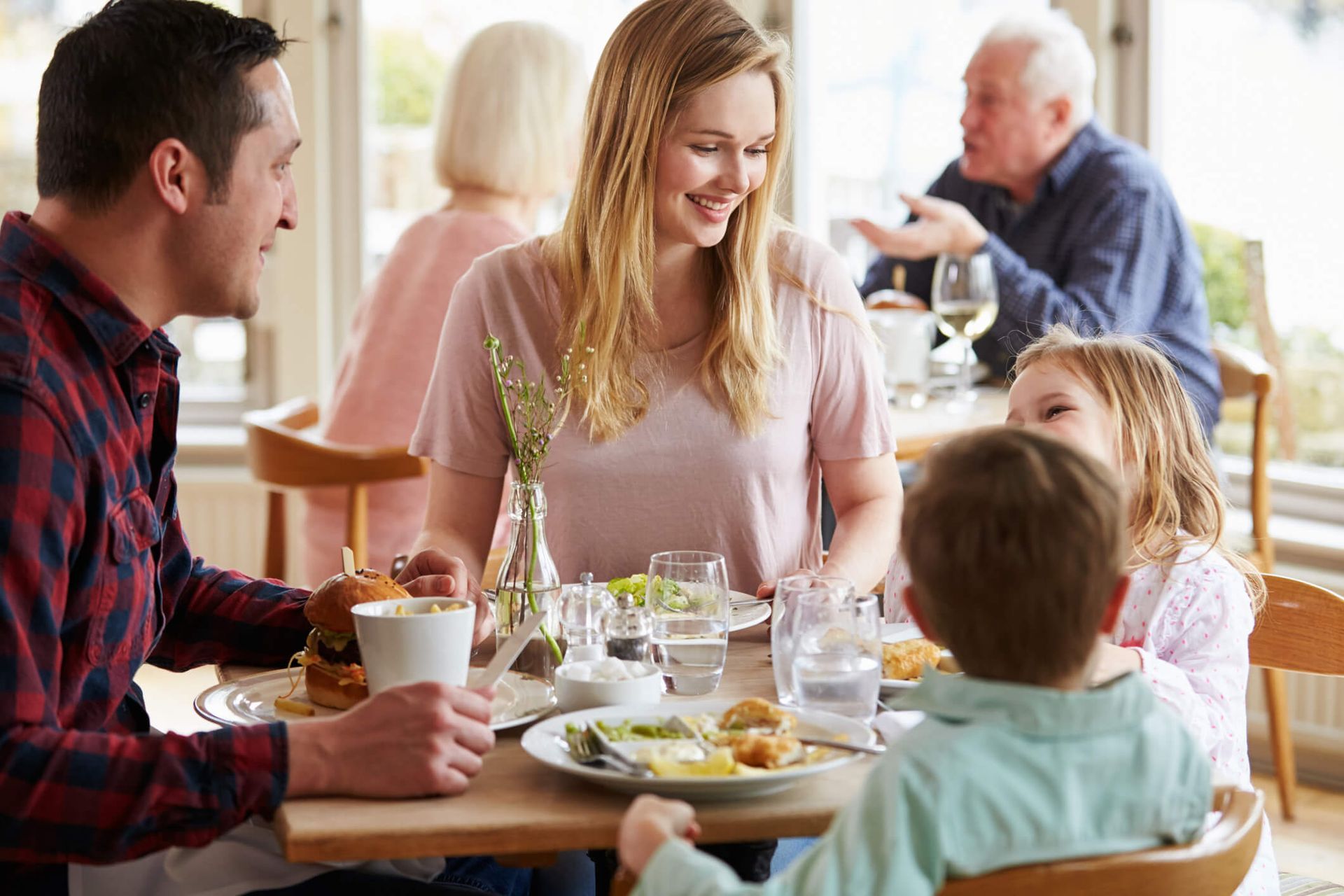 Uma família está sentada à mesa de um restaurante comendo.