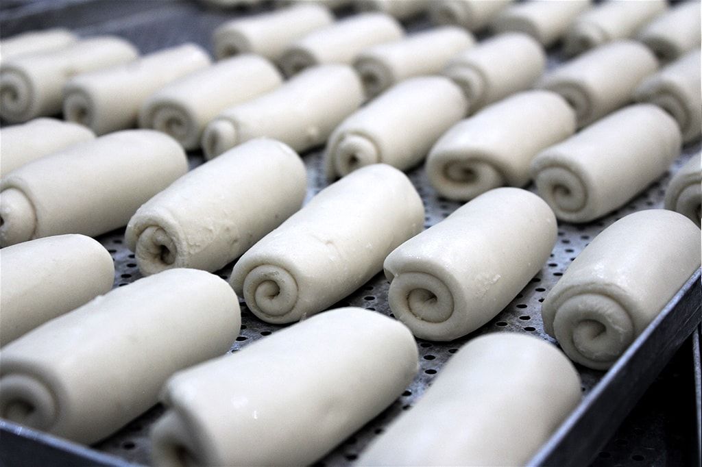 Um monte de pãezinhos brancos estão em uma bandeja de metal