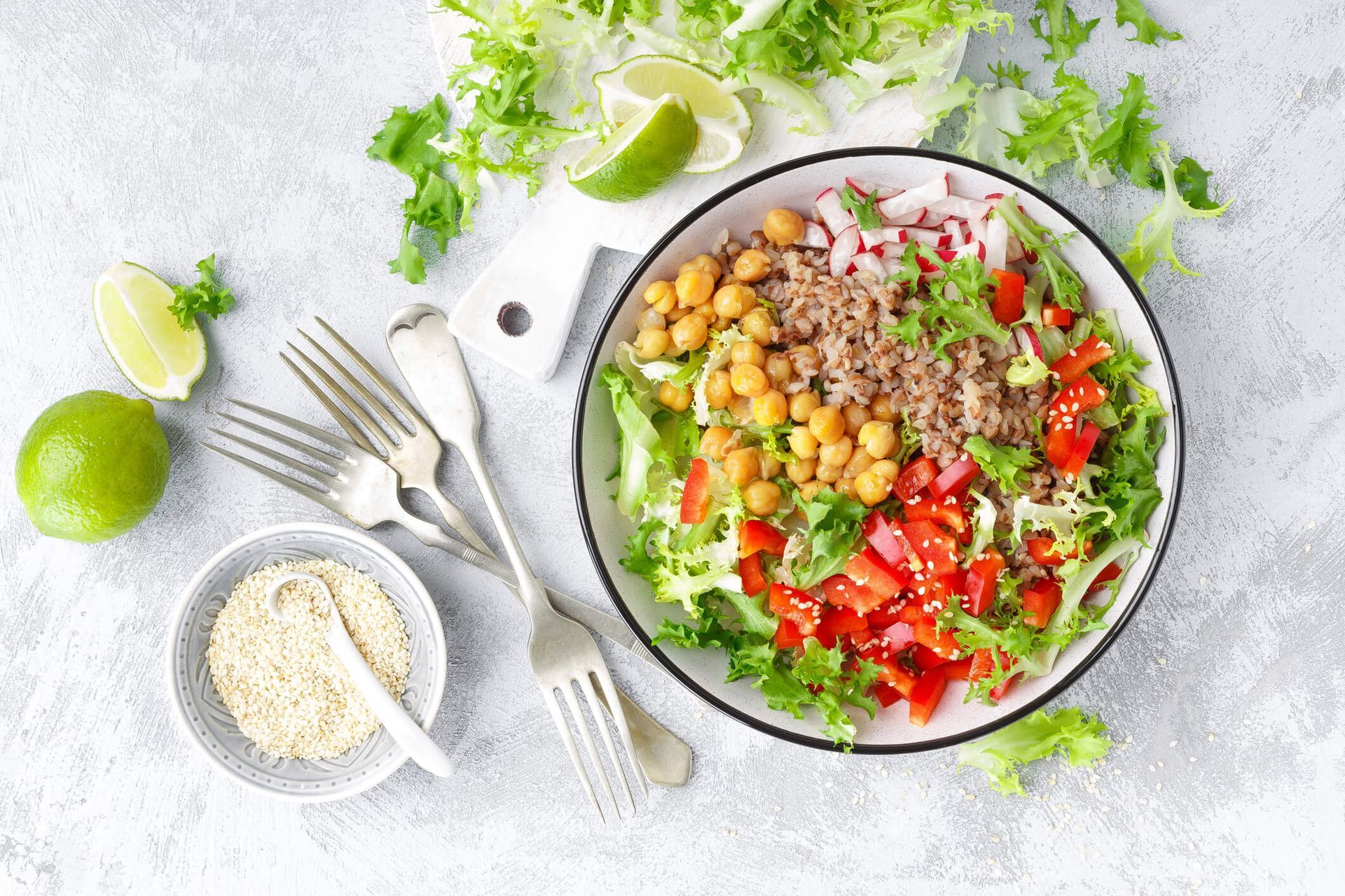 Uma tigela de salada com grão-de-bico, alface, tomate e arroz.
