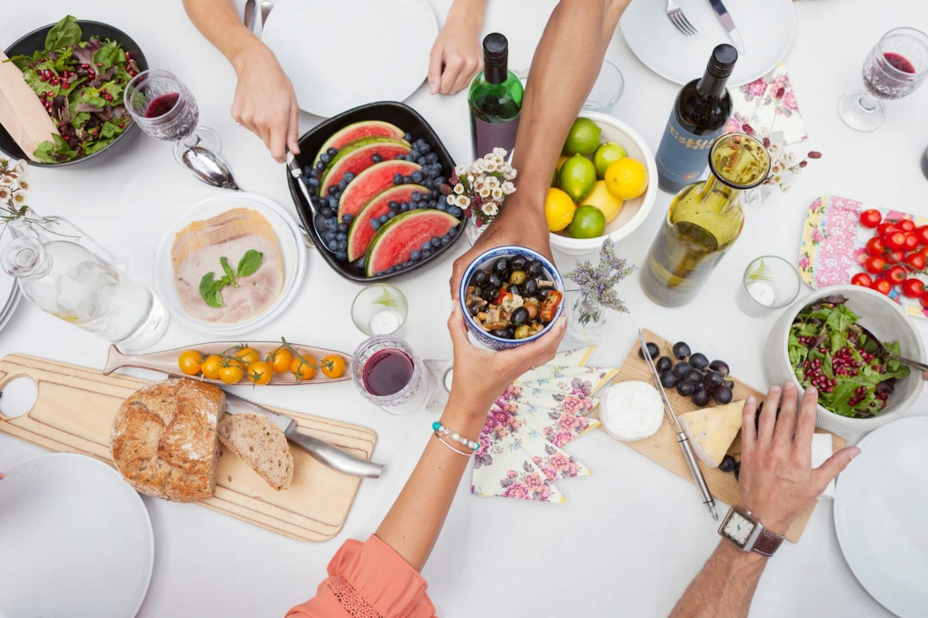 Um grupo de pessoas está sentado à mesa com comida e bebidas.