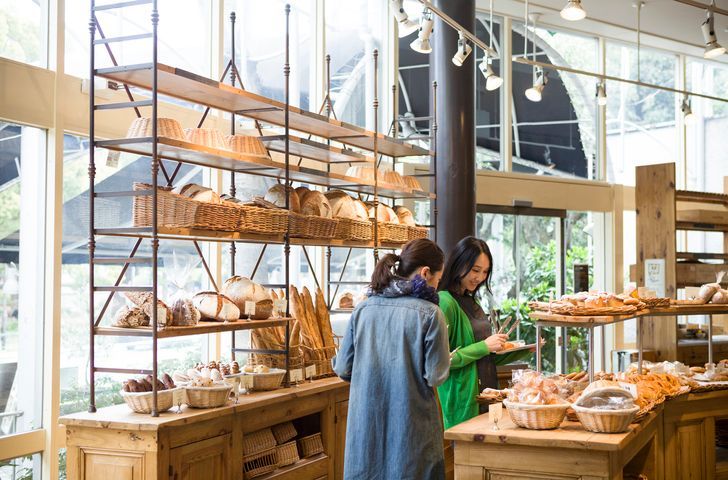 Duas mulheres estão olhando para pão em uma padaria.