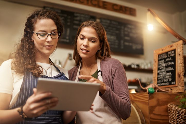 Duas mulheres estão olhando para um tablet em um restaurante.
